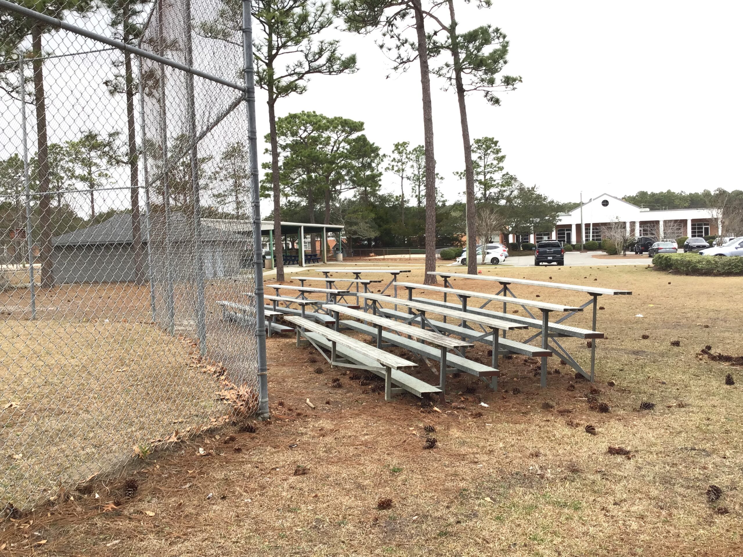 Metal bleachers behind a chain-link fence at a baseball field