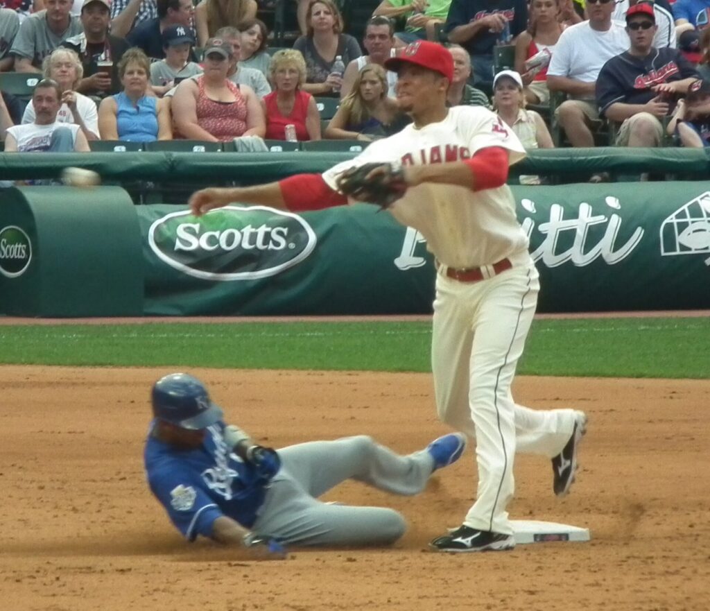 Cleveland middle infielder throws to first after the force at second as a Kansas City runner slides in, the turn on a double play
