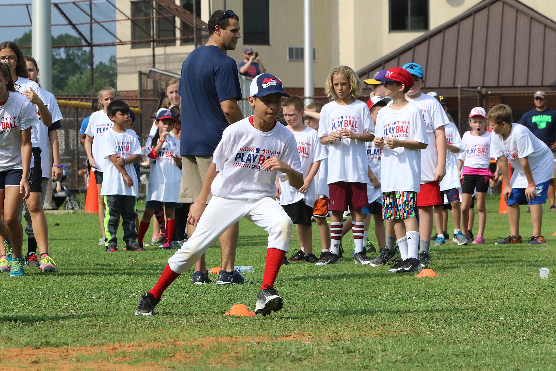 Young player weaving through cones at an agility drill station during an MLB Play Ball event at Fort Bragg