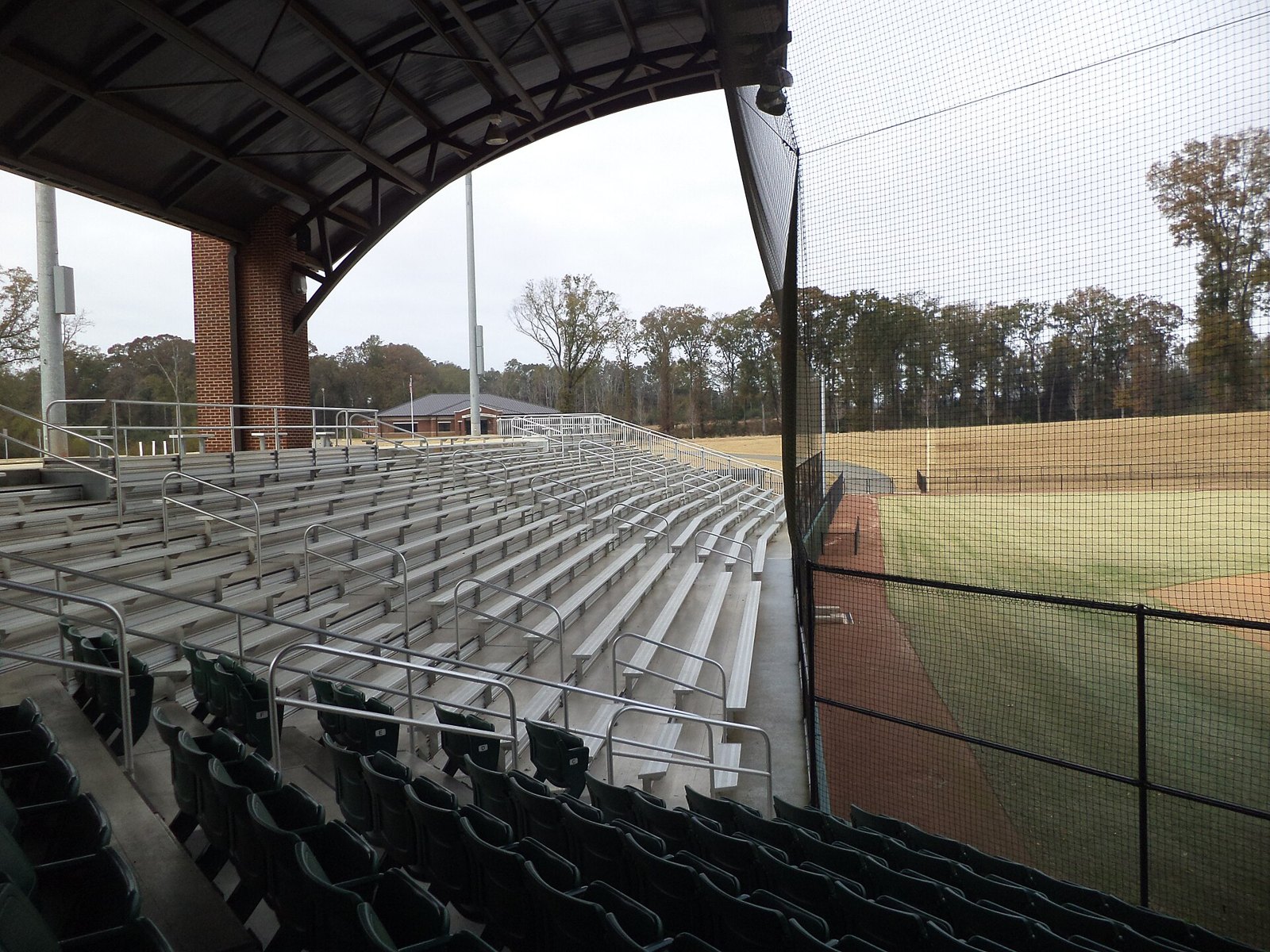Empty covered bleachers at a youth baseball park, like the quiet after tryouts while families wait for the call