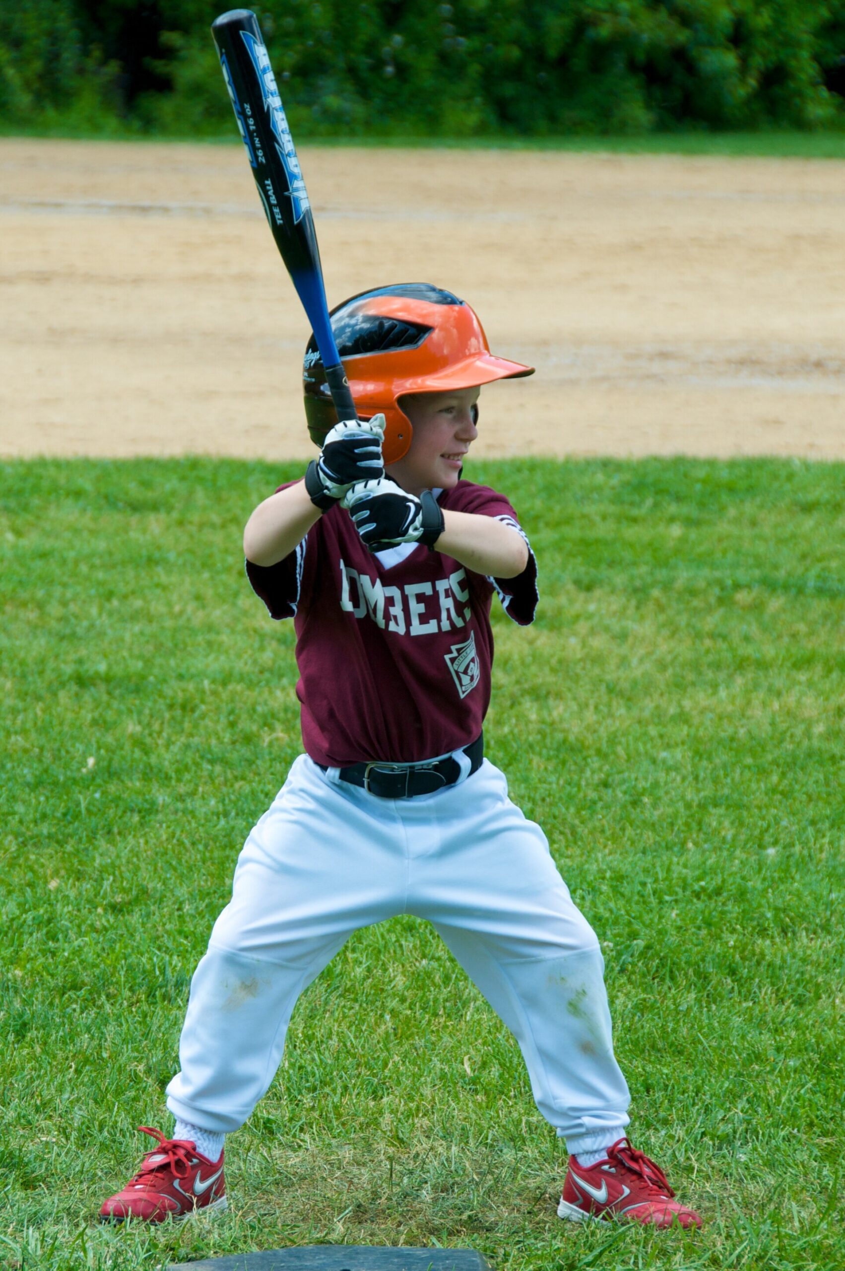 Young Little League batter in an orange helmet waiting on a pitch