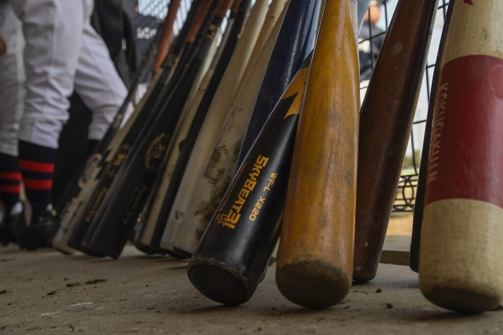 Row of youth baseball bats leaning in a dugout during a tournament game