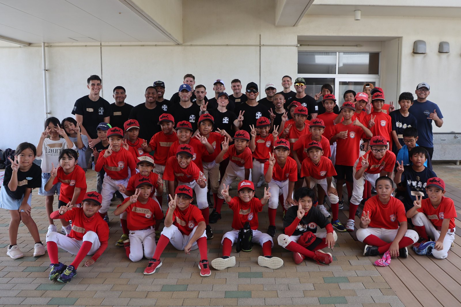 Youth baseball team in matching red uniforms and hats posing for a group photo with adult coaches and volunteers