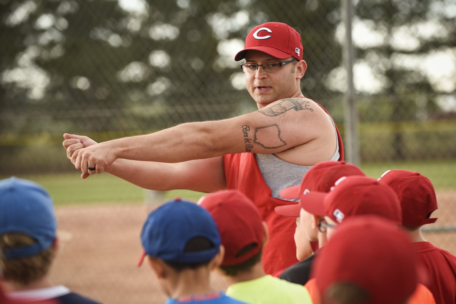Youth baseball coach demonstrating a swing to young players, the kind of coach conversation to have before you switch select baseball teams