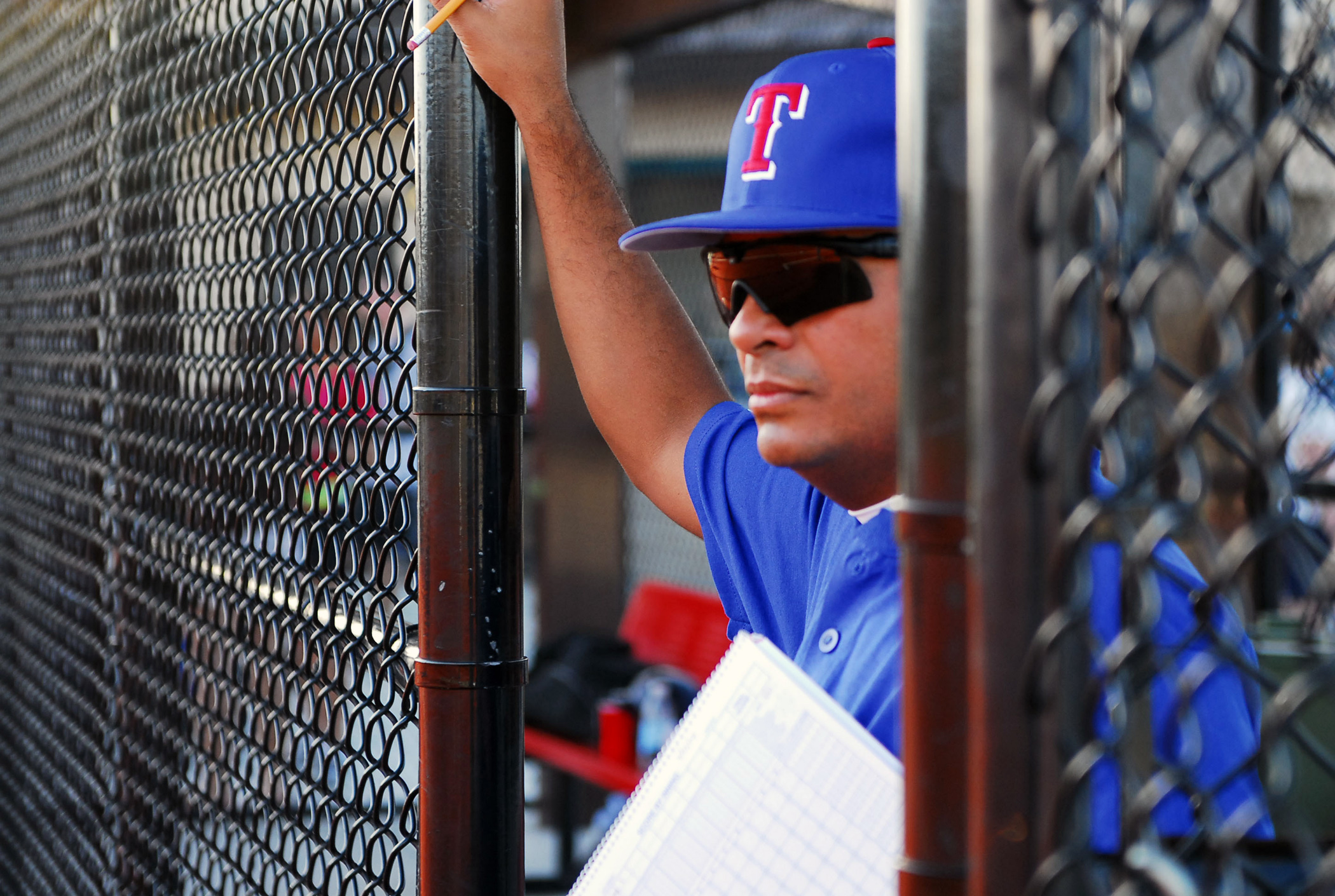 Volunteer youth baseball coach watching the infield from the dugout with a lineup card