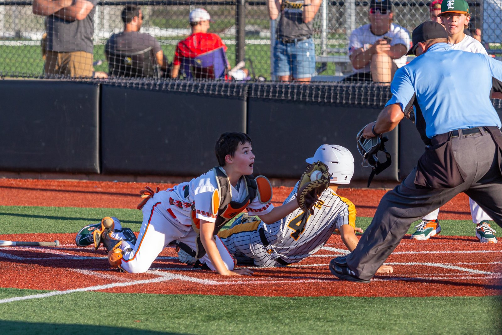 Youth tournament catcher in full gear applying a tag at home plate as the umpire makes the call
